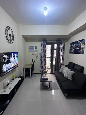 a living room with a black couch and a clock at Bayfront Staycation at The Radiance Manila Pet-Friendly, Free Pool & Gym near Airport, MOA, Star City, Manila World Trade Center & Manila Bay in Manila