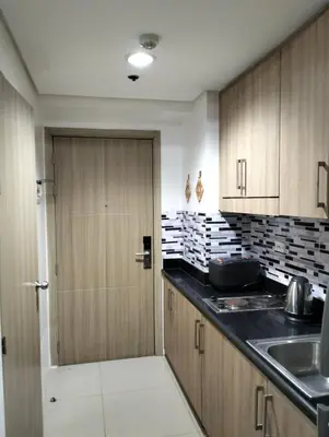 a kitchen with wooden cabinets and a sink and a door at Ellein's Crib At Moa in Manila