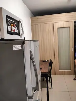 a kitchen with a refrigerator and a table with a tv on top at Ellein's Crib At Moa in Manila
