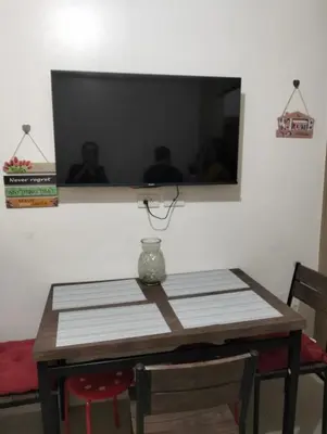 a dining room table with a television on a wall at Ellein's Crib At Moa in Manila
