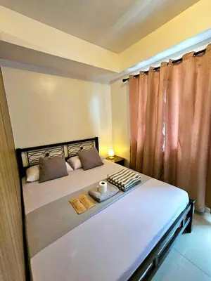 a bedroom with a bed with a tray of food on it at Spacious 1BR beside MOA with Wifi, Netflix, Pool & Washer in Manila