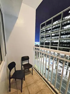 a balcony with two chairs and a view of a building at Spacious 1BR beside MOA with Wifi, Netflix, Pool & Washer in Manila
