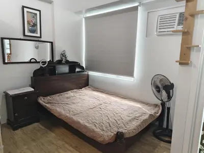 a bed in a room with a fan and a window at Staycation Alabang by Larsen in Manila