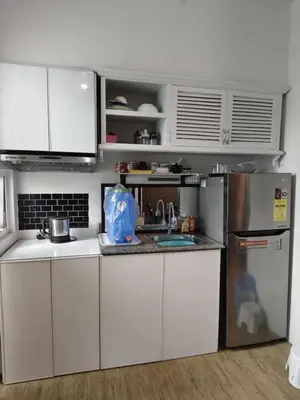 a kitchen with white cabinets and a stainless steel refrigerator at Staycation Alabang by Larsen in Manila