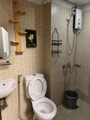a bathroom with a toilet and a sink and a shower at Staycation Alabang by Larsen in Manila