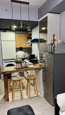 a kitchen with a table and a person in the kitchen at Amaia skies cubao in Manila