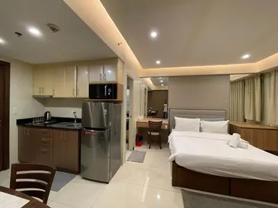 a bedroom with a large bed and a kitchen with a kitchen at Your Home at One Palm Tree Villas near NAIA T3 in Manila
