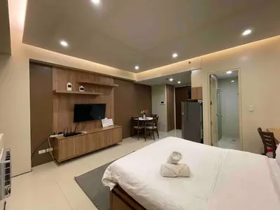a room with a bed and a kitchen and a television at Cozy condo near NAIA T3 at Palm tree villa in Manila
