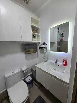 a white bathroom with a toilet and a sink at The Snug Spot at Grace Residences Taguig in Manila