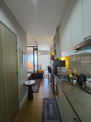 a kitchen with white cabinets and a table in it at The Snug Spot at Grace Residences Taguig in Manila