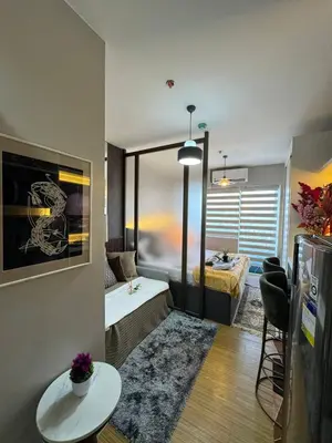 a living room with a room with a bed and a table at The Snug Spot at Grace Residences Taguig in Manila