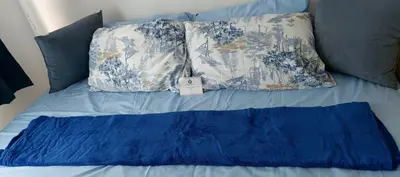a bed with blue and white pillows and a blue blanket at SEA RESIDENCES STAYCATION near MOA by Mae in Manila