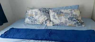 a bed with blue and white pillows on it at SEA RESIDENCES STAYCATION near MOA by Mae in Manila