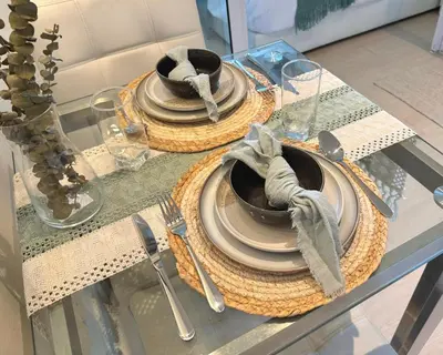 a glass table with plates and utensils on it at Cozy Green 1 BR unit with Balcony Azure Bahamas South in Manila