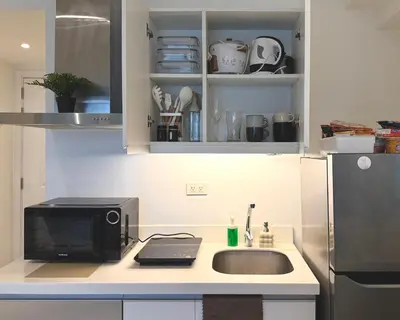 a kitchen with a sink and a microwave at Cozy Green 1 BR unit with Balcony Azure Bahamas South in Manila