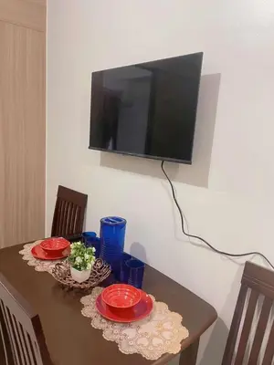 a table with two red plates and a television on a wall at Shore Stay in Manila