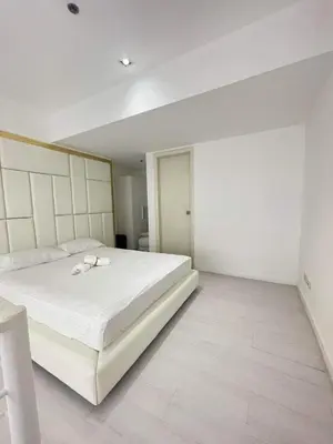 a white bedroom with a large white bed in it at Minimalist 1 Bedroom Loft Makati in Gramercy Residences in Manila
