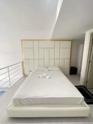 a large white bed with two white shoes on it at Minimalist 1 Bedroom Loft Makati in Gramercy Residences in Manila