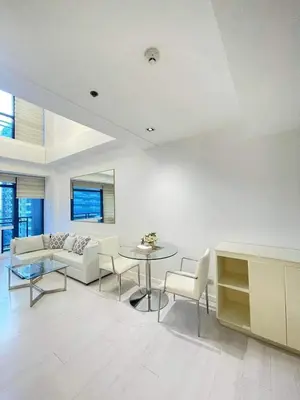 a living room with a couch and a table and chairs at Minimalist 1 Bedroom Loft Makati in Gramercy Residences in Manila