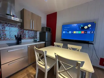 a kitchen with a table with chairs and a tv at Stylish City View Flat Cozy with Netflix WIFI in The Knightsbridge Residences in Manila