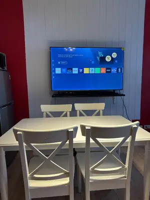 a table with two chairs and a tv on a wall at Stylish City View Flat Cozy with Netflix WIFI in The Knightsbridge Residences in Manila