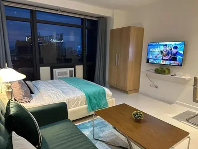 a bedroom with a bed and a tv and a table at Modern Studio with Balcony in The Gramercy Residences in Manila