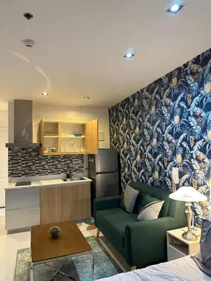 a living room with a green couch and a kitchen at Modern Studio with Balcony in The Gramercy Residences in Manila