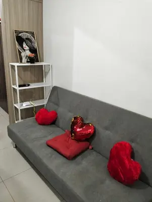 a gray couch with two red pillows on it at Ellein's Condotel in Manila