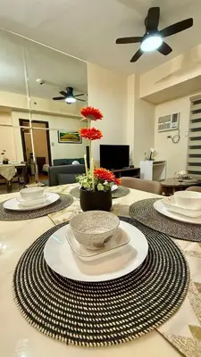 a table with plates and red flowers on top of it at Cozy, aesthetic Pet friendly 1br Condo with balcony in Pasay with Manila Bay View Near MOA & Okada WFH ready Free Pool Acces Gym and Sauna in Manila