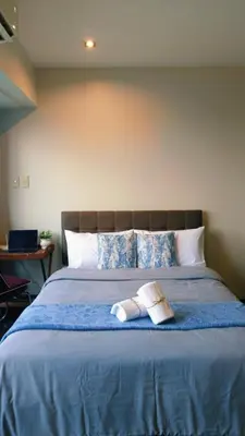 a bed with a blue blanket with a book on it at The Spot 43 Sunrise in Makati in Manila