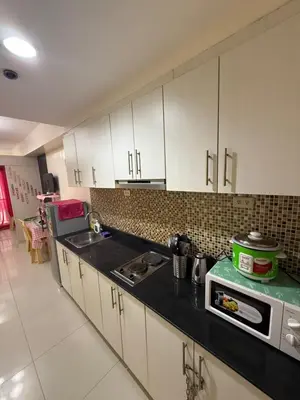 a kitchen with white cabinets and a black counter top at R&K Staycation in Manila