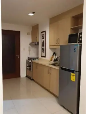 a kitchen with a stainless steel refrigerator and wooden cabinets at Spacious Studio no balcony in Mosaic Tower with WiFi and Smart TV in Manila