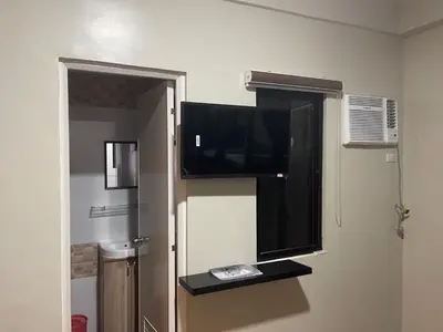 a room with a flat screen tv and a window at The Budget Inn in Manila