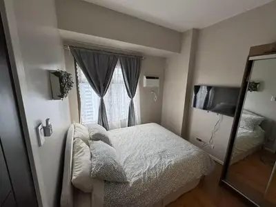 a small bedroom with a bed and a mirror at Cooper's Place in Manila