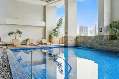 a hotel pool with chairs and a view of the city at CABIN STUDIO in KL TOWER, Greenbelt, Makati! Max Capacity 6 pax! in Manila