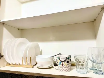 a shelf with white plates and glasses on it at Shore 2 tower 2 near moa in Manila