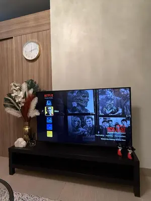 a flat screen tv in a living room with a clock at Shore2 Residence Pasay by N&R Valmont in Manila