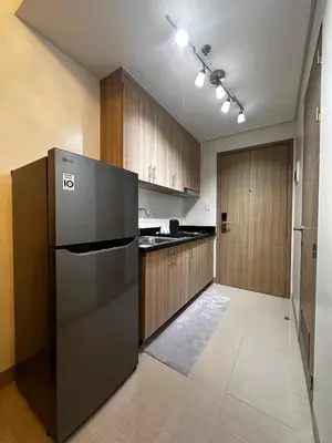 a kitchen with a black refrigerator and wooden cabinets at Shore2 Residence Pasay by N&R Valmont in Manila