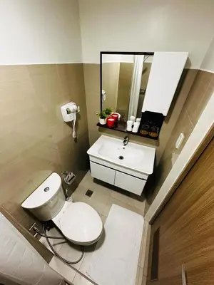 a bathroom with a toilet and a sink and a mirror at Shore2 Residence Pasay by N&R Valmont in Manila