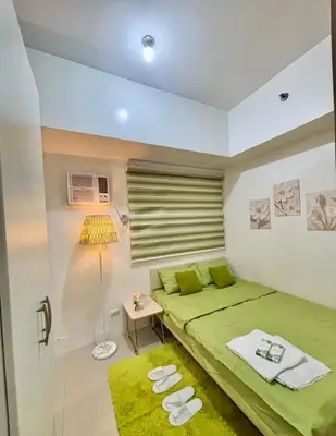 a bedroom with a green bed and a lamp at Cozy Nook in the City of Mandaluyong in Manila