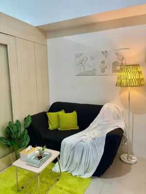 a living room with a black couch and a table at Cozy Nook in the City of Mandaluyong in Manila