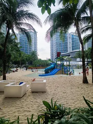a playground on a beach with palm trees and buildings at Azure Urban Resort Staycation in Manila