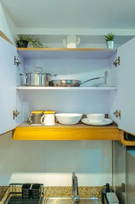 a kitchen with some pots and pans on a shelf at Consider It Yours - Stay Cozy with City Views in Manila
