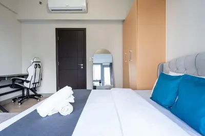 a bedroom with a bed with a desk and a chair at Uptown Parksuites Upscale Spacious Cor Unit Balcony and Views in Manila