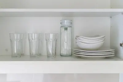a shelf with glasses and plates and a bottle at Uptown Parksuites Upscale Spacious Cor Unit Balcony and Views in Manila