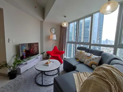 a living room with a blue couch and a red chair at Uptown Parksuites Upscale Spacious Cor Unit Balcony and Views in Manila