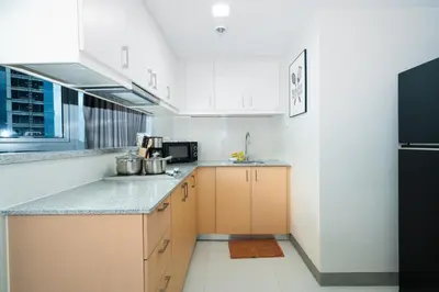 a kitchen with white cabinets and a black refrigerator at Uptown Parksuites Upscale Spacious Cor Unit Balcony and Views in Manila