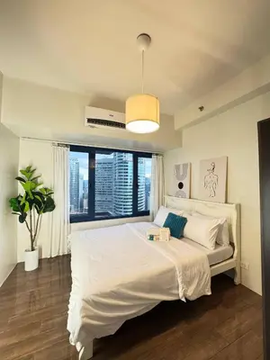 a bedroom with a large white bed with a window at Entire Place in Central Makati in Manila
