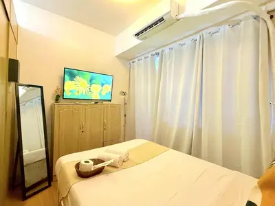 a hotel room with a bed and a television at Instaworthy Space near BGC NAIA at Grace Res in Manila