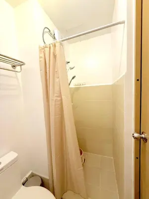 a bathroom with a shower curtain and a toilet at Instaworthy Space near BGC NAIA at Grace Res in Manila